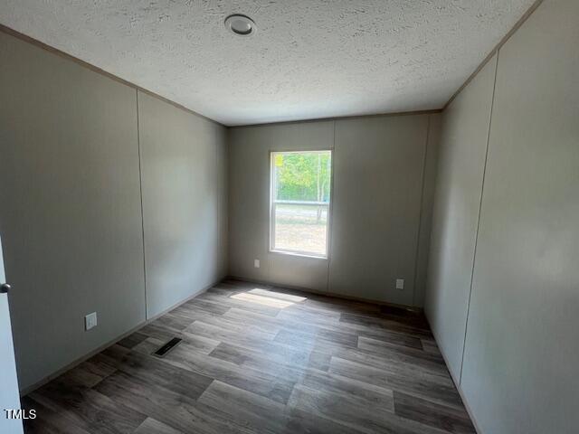 spare room featuring a decorative wall, wood finished floors, and a textured ceiling