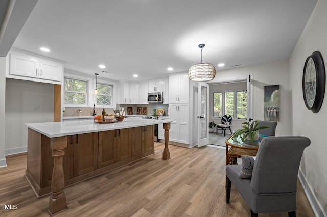 kitchen featuring tasteful backsplash, baseboards, white cabinetry, and a wealth of natural light