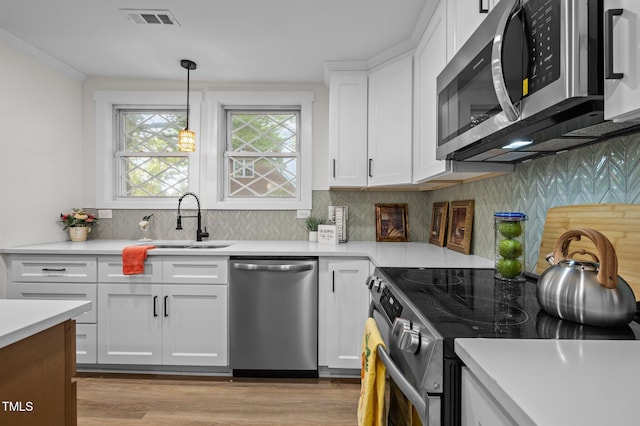 kitchen with visible vents, light countertops, a sink, stainless steel appliances, and backsplash