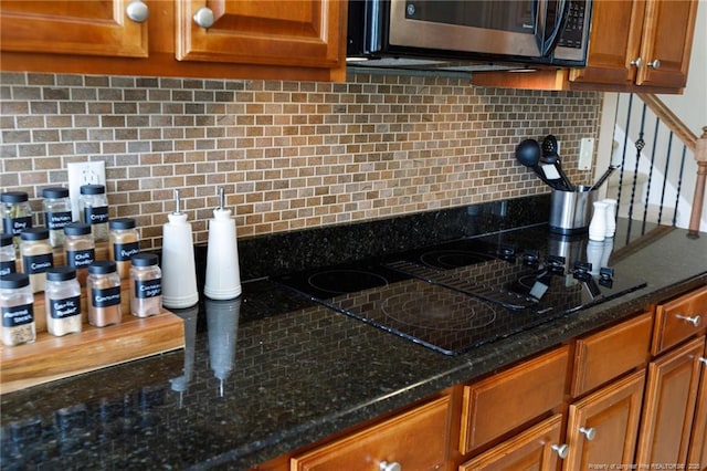 308 St Martins Pl, Fayetteville, NC 28311 - kitchen with dark stone counters, stainless steel microwave, black electric stovetop, brown cabinets, and decorative backsplash