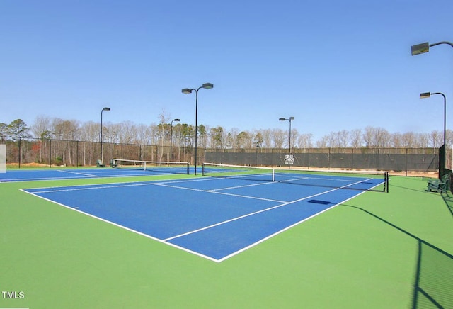 view of tennis court featuring community basketball court and fence