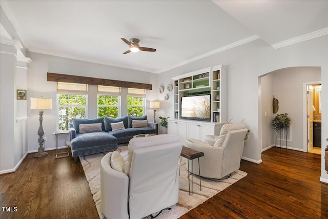 living area featuring arched walkways, a ceiling fan, ornamental molding, wood finished floors, and baseboards