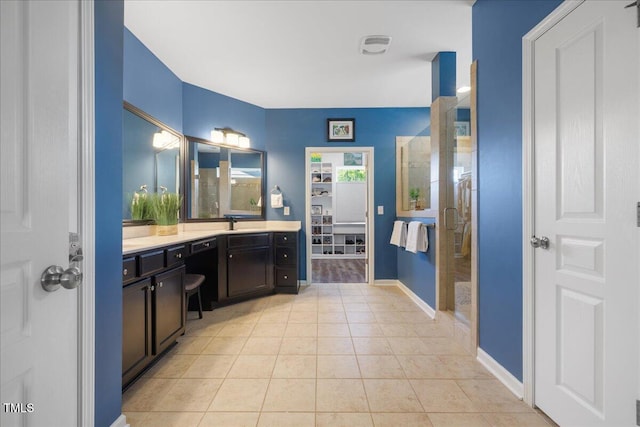 full bathroom featuring vanity, a shower with shower door, tile patterned floors, and baseboards