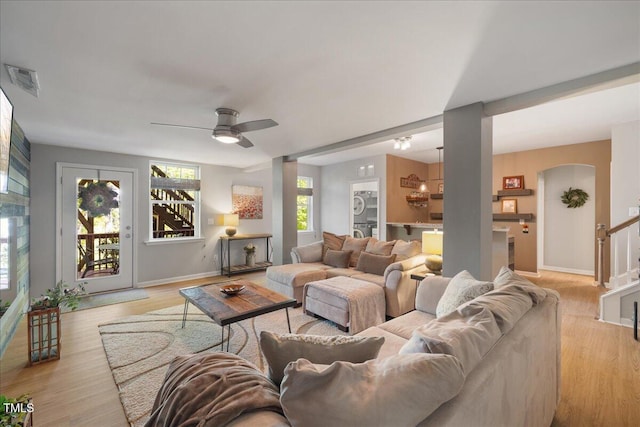 living area featuring healthy amount of natural light, baseboards, ceiling fan, and light wood-type flooring
