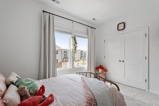 carpeted bedroom featuring baseboards, visible vents, and a closet