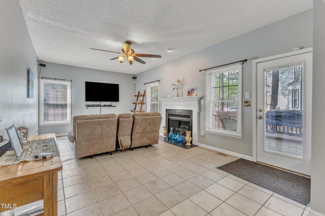 9332 Leslieshire Dr, Raleigh, NC 27615 - living area with light tile patterned floors, ceiling fan, a fireplace, a textured ceiling, and baseboards