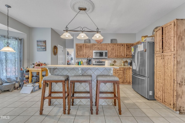 9332 Leslieshire Dr, Raleigh, NC 27615 - kitchen featuring tasteful backsplash, light tile patterned floors, light countertops, decorative light fixtures, and stainless steel appliances