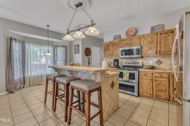 9332 Leslieshire Dr, Raleigh, NC 27615 - kitchen featuring stainless steel appliances, light tile patterned floors, backsplash, and a kitchen island