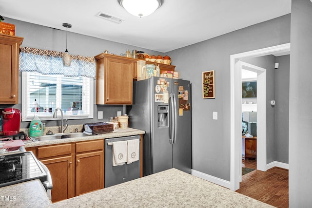 kitchen featuring light countertops, wood finished floors, visible vents, a sink, and appliances with stainless steel finishes
