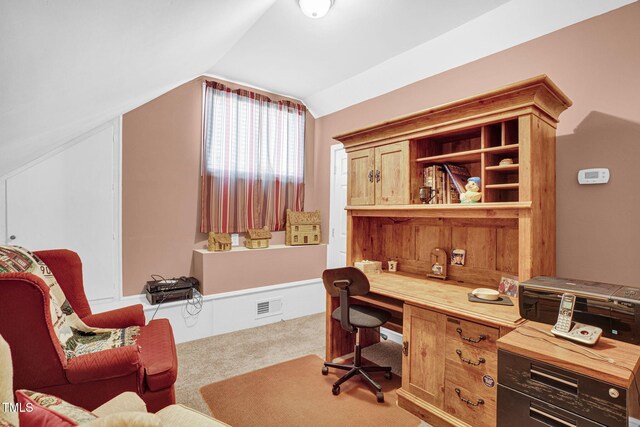 carpeted office space with vaulted ceiling, visible vents, and built in study area