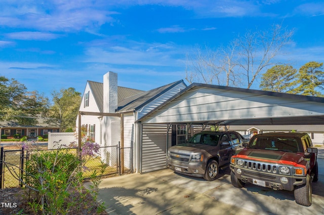 view of front of home with fence, a chimney, a gate, and a carport