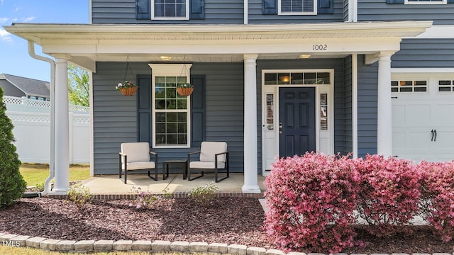 entrance to property featuring a porch, a garage, and fence