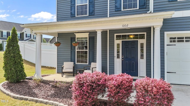 view of exterior entry featuring a porch and fence
