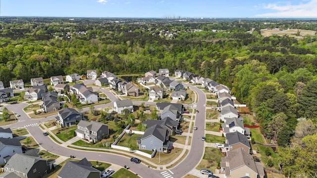 aerial overview of property's location featuring nearby suburban area and a heavily wooded area