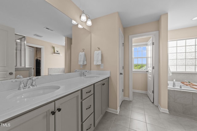 bathroom with baseboards, tile patterned flooring, double vanity, and a garden tub