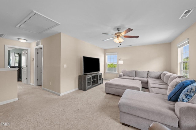 living room with attic access, ceiling fan, light colored carpet, and baseboards
