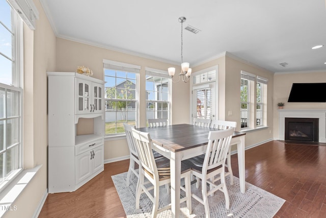 dining space featuring a chandelier, ornamental molding, wood finished floors, baseboards, and a fireplace with flush hearth