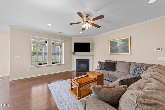 living room featuring crown molding, ceiling fan, wood finished floors, a fireplace with flush hearth, and baseboards