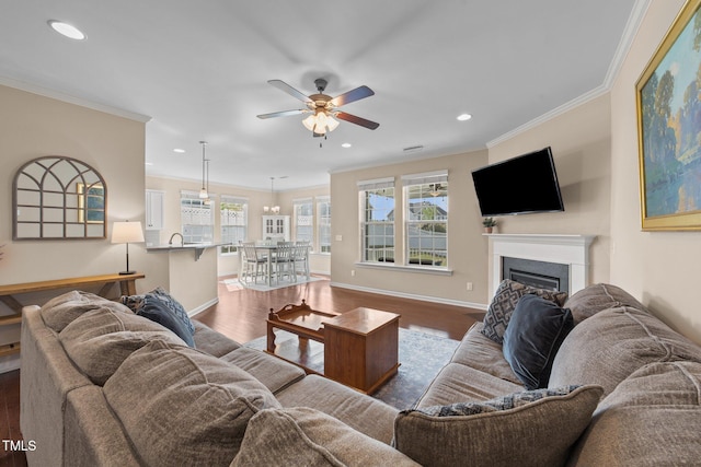 living area featuring ornamental molding, a ceiling fan, a glass covered fireplace, recessed lighting, and dark wood-type flooring