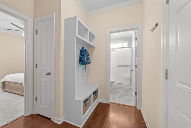 mudroom with dark wood finished floors, crown molding, and baseboards