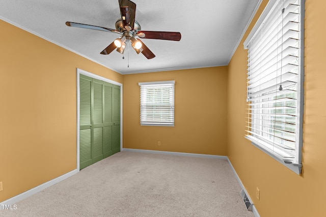 unfurnished bedroom featuring crown molding, a closet, visible vents, and carpet floors