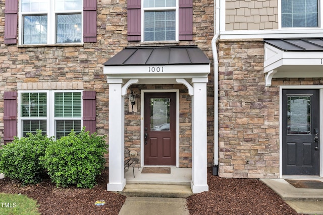 doorway to property featuring stone siding, a standing seam roof, and metal roof