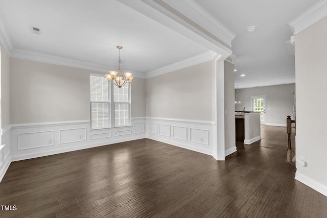 unfurnished dining area featuring wainscoting, a chandelier, dark wood-type flooring, ornamental molding, and a decorative wall