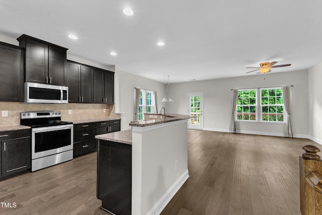 kitchen featuring stainless steel appliances, wood finished floors, backsplash, healthy amount of natural light, and recessed lighting