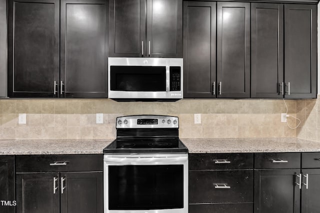 kitchen with appliances with stainless steel finishes, tasteful backsplash, dark cabinetry, and light stone countertops