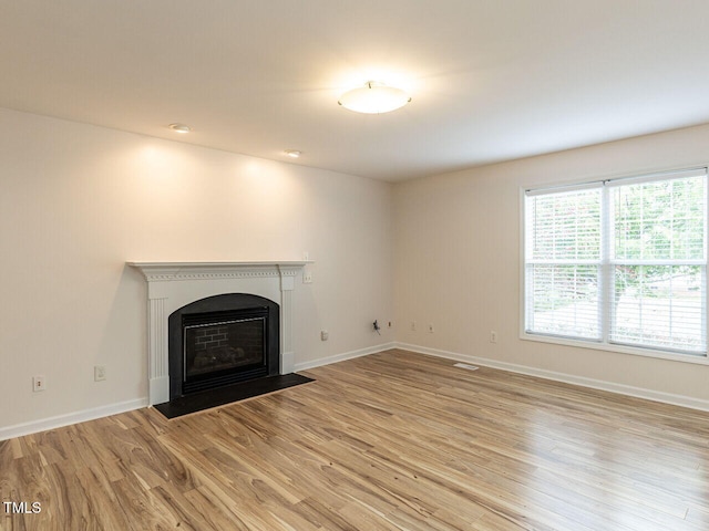 unfurnished living room featuring a fireplace with flush hearth, light wood-style flooring, and baseboards