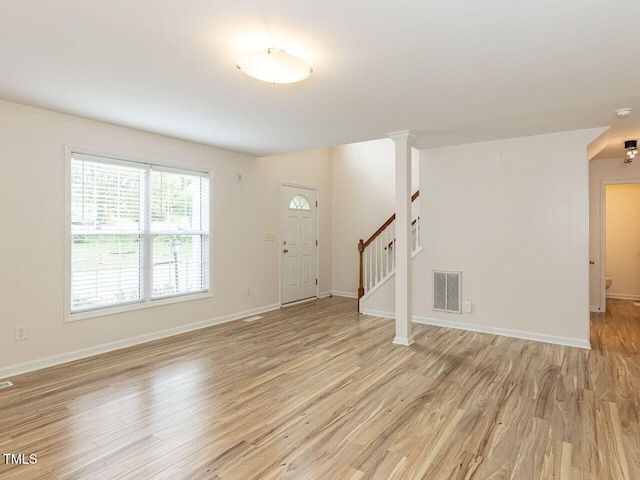 unfurnished living room with baseboards, stairs, visible vents, and light wood-type flooring
