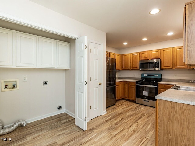 kitchen with recessed lighting, stainless steel appliances, light countertops, a sink, and light wood-style flooring