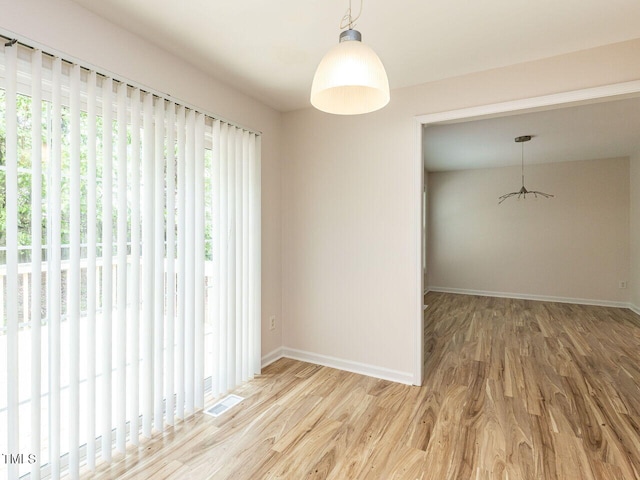 empty room with visible vents, wood finished floors, and baseboards