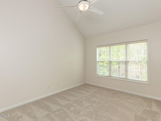 empty room featuring lofted ceiling, a ceiling fan, baseboards, and light carpet