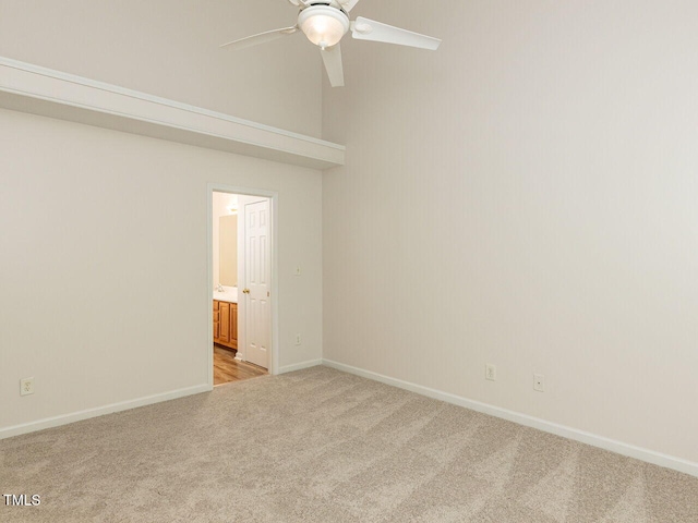 spare room with a ceiling fan, baseboards, and light colored carpet