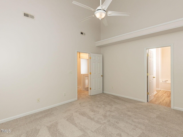 unfurnished bedroom featuring visible vents, baseboards, a high ceiling, and carpet floors