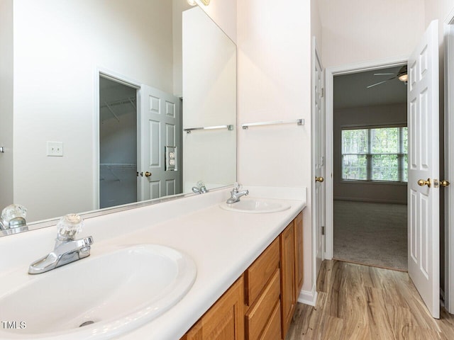 full bath with double vanity, a spacious closet, wood finished floors, and a sink