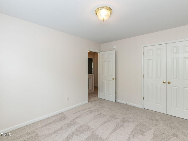 unfurnished bedroom with carpet, a closet, and baseboards