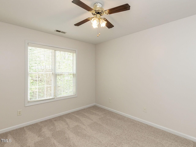 carpeted spare room featuring visible vents, baseboards, and ceiling fan
