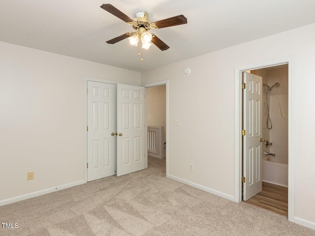 unfurnished bedroom featuring carpet flooring, ensuite bathroom, baseboards, a closet, and ceiling fan