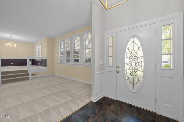1304 Deboy St, Raleigh, NC 27606 - foyer with baseboards, a chandelier, carpet flooring, crown molding, and stone finish flooring