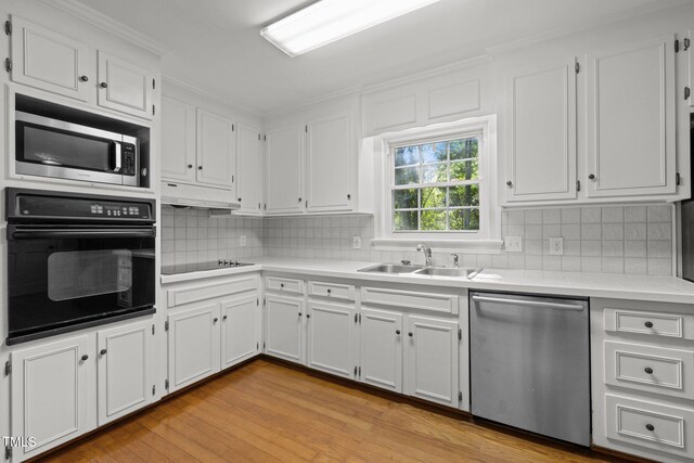 1304 Deboy St, Raleigh, NC 27606 - kitchen with tasteful backsplash, white cabinets, a sink, black appliances, and light wood finished floors