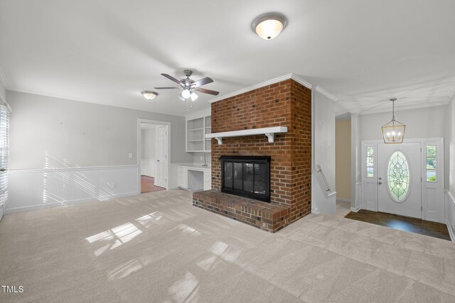 1304 Deboy St, Raleigh, NC 27606 - unfurnished living room with built in features, a brick fireplace, carpet, crown molding, and ceiling fan with notable chandelier