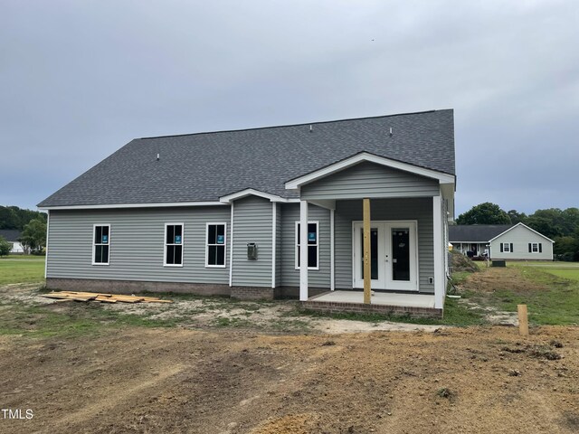 rear view of property featuring roof with shingles and french doors