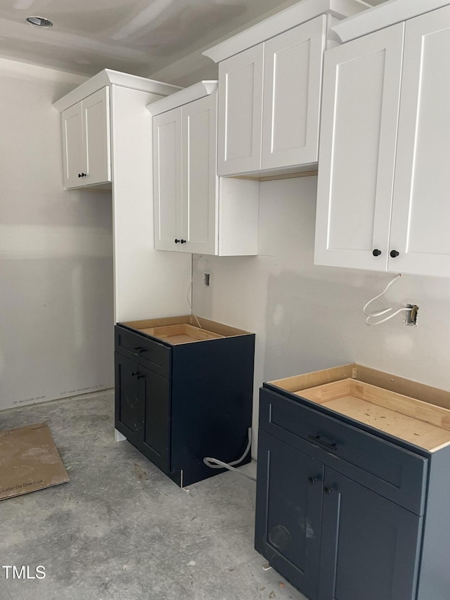 kitchen featuring unfinished concrete flooring and white cabinets