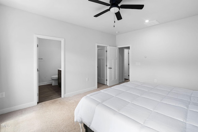 bedroom featuring a spacious closet, baseboards, ensuite bath, and light colored carpet