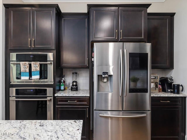 kitchen with appliances with stainless steel finishes, backsplash, light stone countertops, and dark brown cabinetry