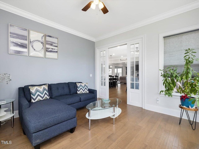 living area featuring crown molding, wood finished floors, ceiling fan, and baseboards