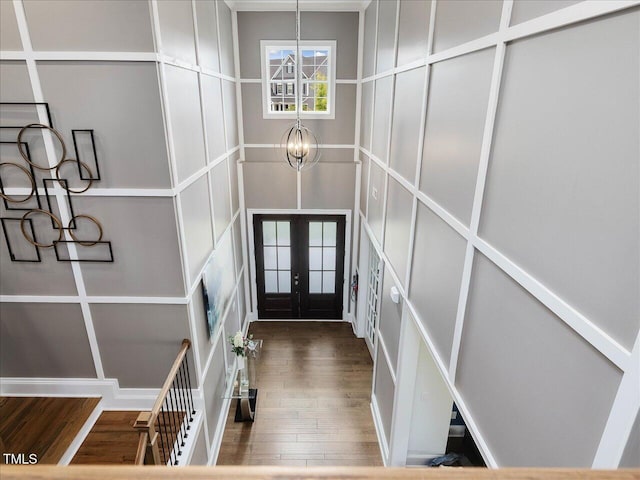 entryway with french doors, a chandelier, and wood finished floors