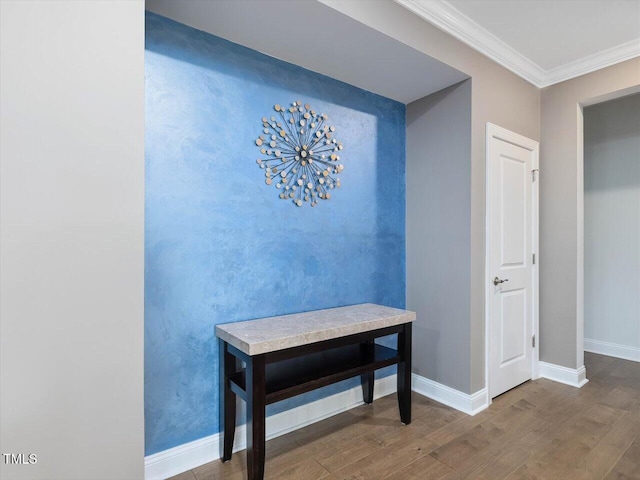 corridor featuring wood finished floors, ornamental molding, and baseboards